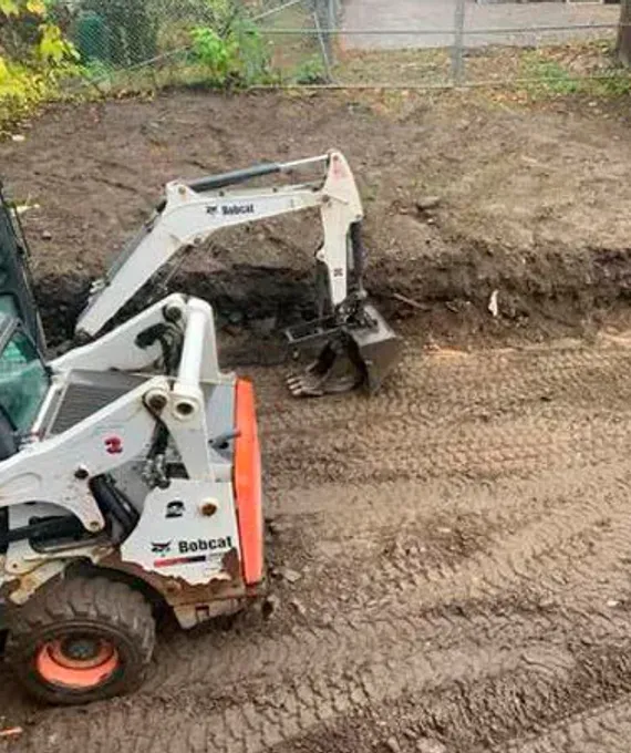 Skid steer shaping topsoil for proper drainage