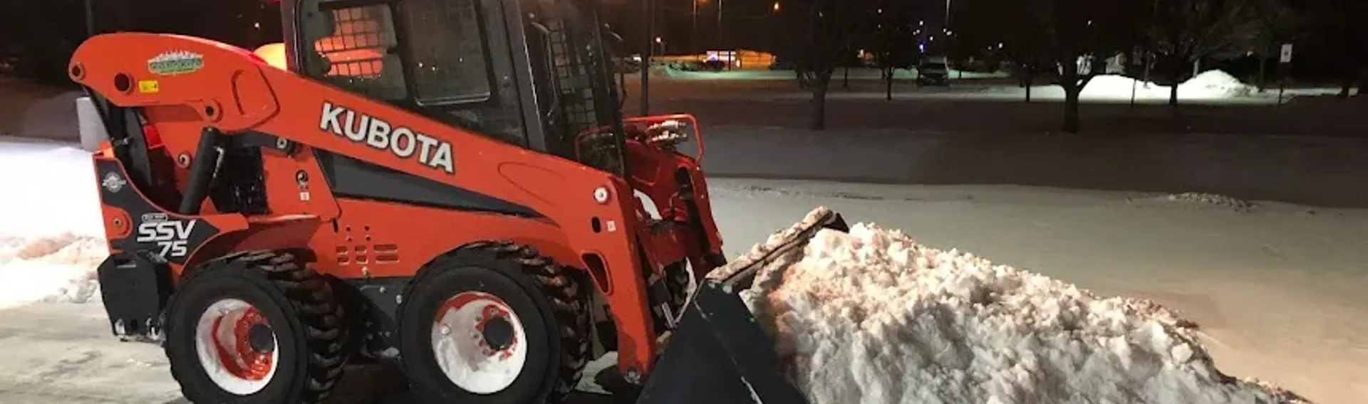 Skid steer clearing snow from commercial parking lot
