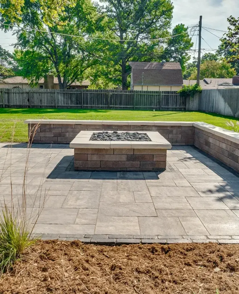 Custom paving stone patio featuring a built-in fire pit and curved seating wall at dusk in Edmonton.