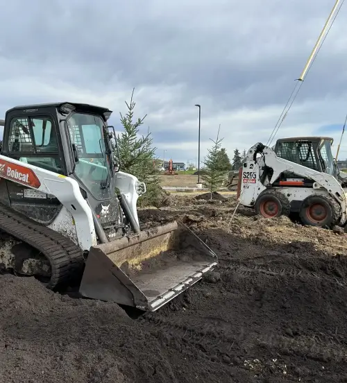 Skid steers performing commercial landscaping construction and property maintenance in Edmonton.