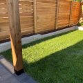 A newly installed structural retaining wall and pressure-treated wood fence built in an Edmonton residential backyard to manage a steep slope and provide privacy.