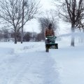Snow removal crew clearing a residential driveway in Edmonton with the cost of service in mind