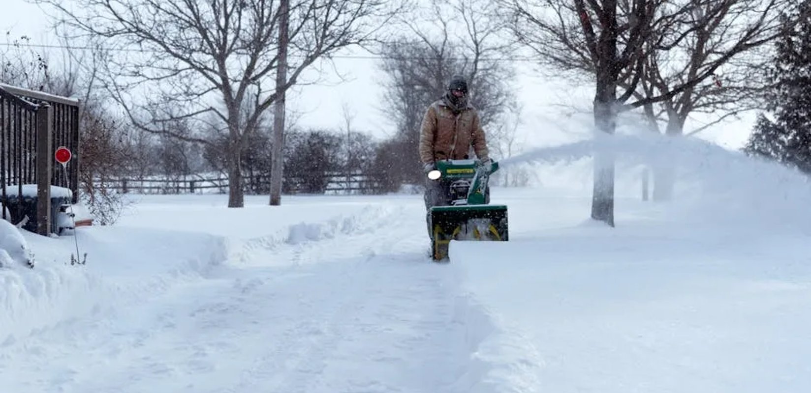 Snow removal crew clearing a residential driveway in Edmonton with the cost of service in mind