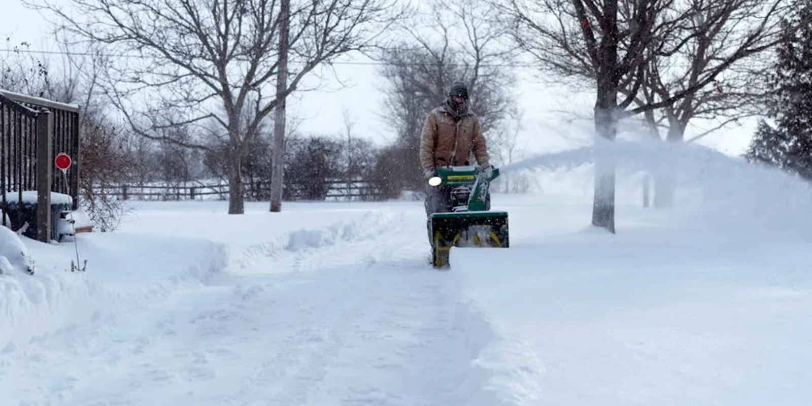 Snow removal crew clearing a residential driveway in Edmonton with the cost of service in mind