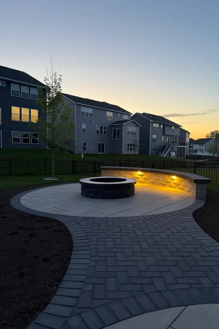 Front yard residential landscape design in Edmonton featuring fresh mulch, shrubs, and a natural stone retaining wall.