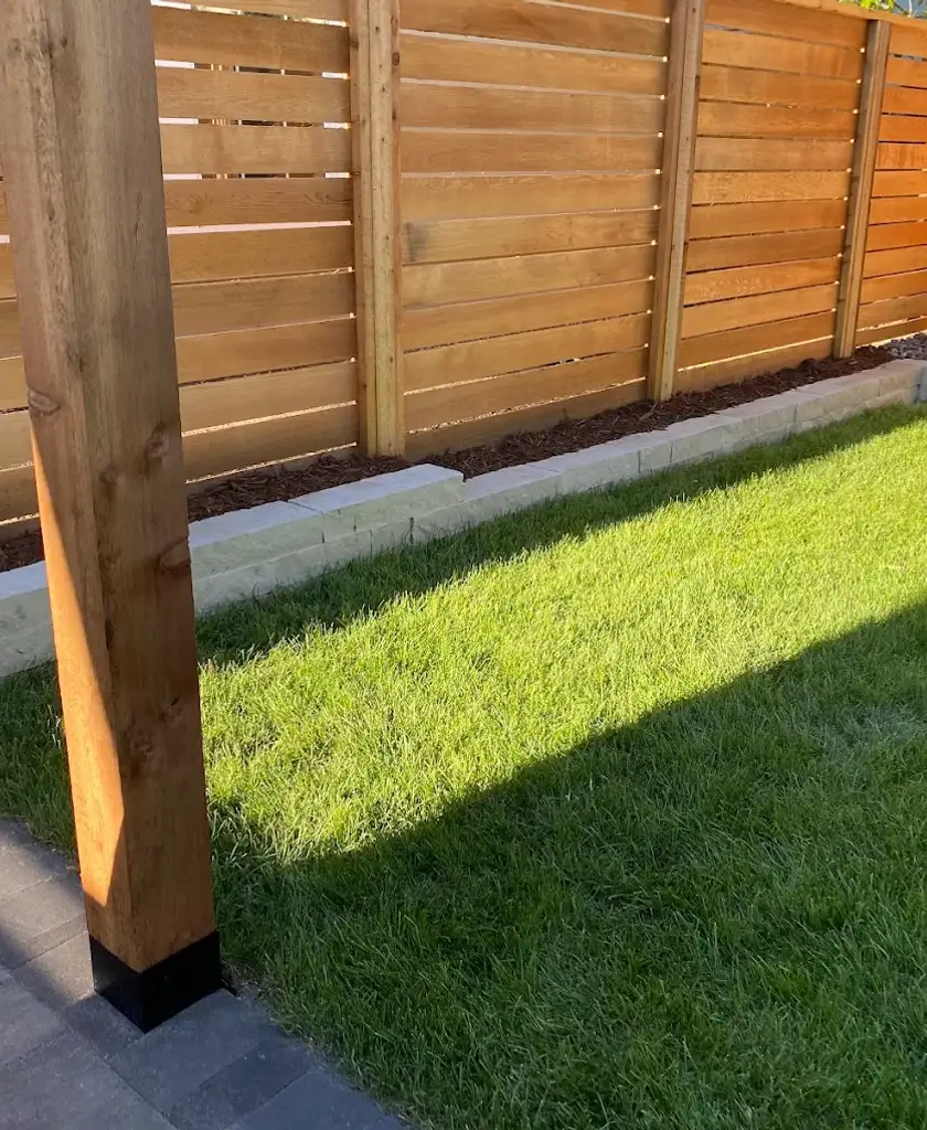 Small retaining wall and horizontal wood fence installation next to fresh sod in Sherwood Park.