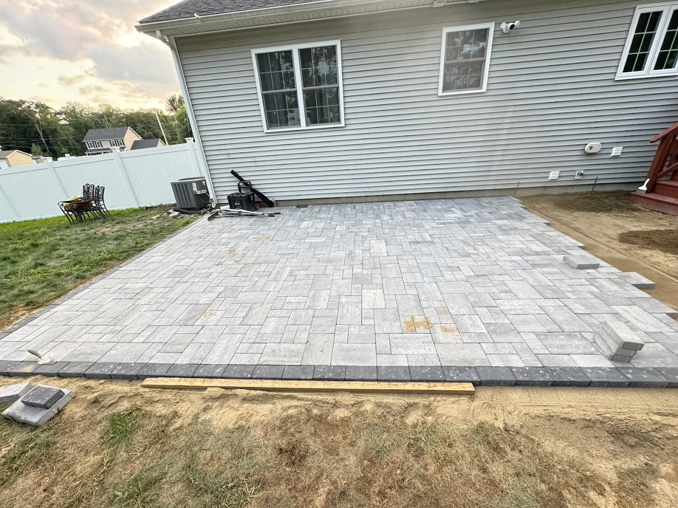 Beautiful stone patio with modern outdoor seating and lush landscaping, perfect for relaxing in a stylish backyard setting.